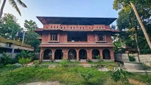an old red brick building with a roof at Maison sangham in Varkala
