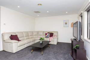 a living room with a white couch and a tv at Spacious 4-Bedroom Family Retreat with Pool at Tarneit in Tarneit
