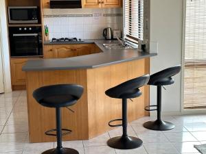 a kitchen with a counter with three bar stools at Spacious 4-Bedroom Family Retreat with Pool at Tarneit in Tarneit