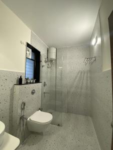 a bathroom with a toilet and a glass shower at Chic 1BHK Apartment - Pool, Gym, Amenities Near Candolim Beach in Candolim