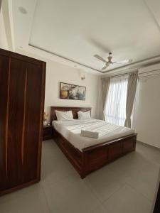 a bedroom with a large wooden bed with a window at Chic 1BHK Apartment - Pool, Gym, Amenities Near Candolim Beach in Candolim +44 photos