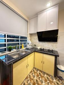 a kitchen with yellow cabinets and a sink at Homestay Kuala Perlis in Kuala Perlis