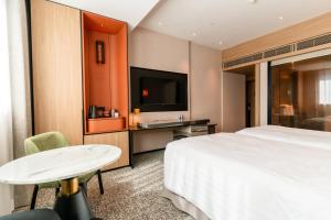 a hotel room with a bed and a table and a tv at Nathan Hotel in Hong Kong