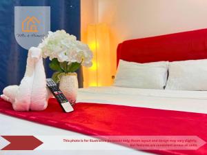 une chambre d'hôtel avec un lit avec une télécommande et des fleurs dans l'établissement ImpianKU at HYVE SOHO Cyberjaya - 2BR - Wifi, à Cyberjaya 8 autres photos