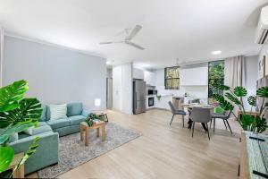 a living room with a blue couch and a kitchen at Sandalwood Oasis - Tropical Serenity near Waterfront in Nightcliff