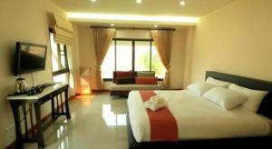 a bedroom with a bed and a desk and a television at So Herbs at Home in Chiang Rai