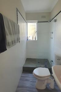 a white bathroom with a toilet and a sink at Sufi'Sawd Guest Rooms Muizenberg in Muizenberg +30 photos