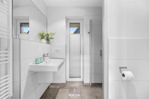 ein weißes Badezimmer mit Waschbecken und Dusche in der Unterkunft Meerverliebt in Büsum