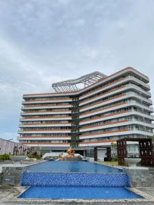 - un grand bâtiment avec une grande piscine en face dans l'établissement Deluxe Room Sea View Pool Golf Nuvasa Bay Kalani Tower, à Pulau Nongsa