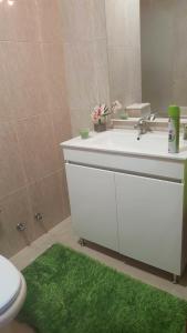 a bathroom with a sink and a toilet and a green rug at Apartamento Moderno e Elegante in Ponta Delgada