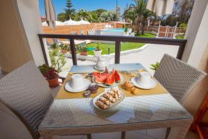 einen Tisch mit Speisen auf einem Balkon mit Poolblick in der Unterkunft Villa Sunset B&B/Apartments in Fontane Bianche