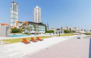 a row of benches in a park with buildings at 2 Bedroom Condo R258 Veranda Pattaya Beachfront in Na Jomtien
