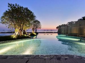 a large swimming pool with trees in the water at 2 Bedroom Condo R258 Veranda Pattaya Beachfront in Na Jomtien