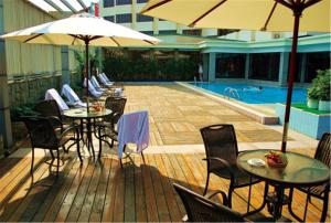 una terraza con mesas, sillas, sombrillas y una piscina en Zhongshan International Hotel, en Zhongshan
