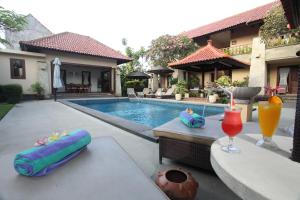 a swimming pool with a drink on a table next to a house at Pondok Ayu in Sanur