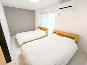 two beds in a room with white walls at Vacation House 3 in Funabashi