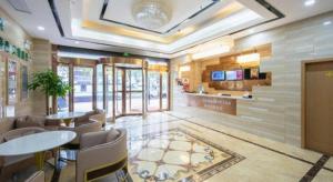 a lobby with tables and chairs in a restaurant at GreenTree Inn Wuxi Huishan District Xizhang Metro Station Express Hotel in Wuxi
