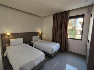 a hotel room with two beds and a window at Masaken Hotel Apartment in Amman