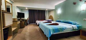 a hotel room with two beds and a television at Pension Zum Ross in Karon Beach