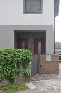 a house with a hedge in front of a building at Le Sartorie in Pozzuolo del Friuli