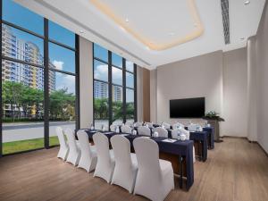 a conference room with a table and chairs and a screen at Holiday Inn Resort Wanning Shenzhou Peninsula by IHG in Wanning