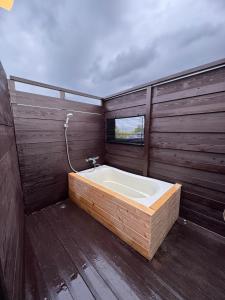 a bathroom with a bath tub with a window at Fujimi no Oka Auto Campsite - Vacation STAY 27845v in Fuji