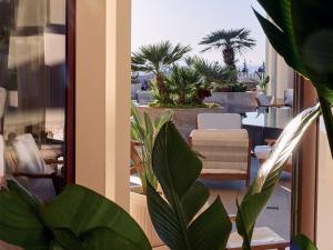 a balcony with a view of a patio with palm trees at Grecotel LUXME Kos in Kos Town
