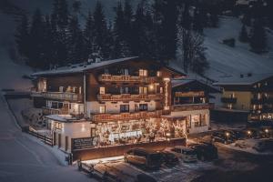 a large building in the snow at night at Hotel & Appartements Tiroler Buam in Saalbach Hinterglemm