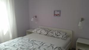 a white bedroom with a bed and a window at Apartment Diminic Melin in Cres