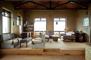 ein Wohnzimmer mit Stühlen, Tischen und Fenstern in der Unterkunft Hananoie - A Permaculture Resort in Pokhara