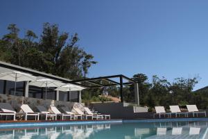 a pool with chairs and umbrellas next to the water at Quinta Vale da Roca in Sintra