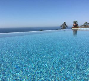 a large pool of blue water with a house in the background at Quinta Vale da Roca in Sintra
