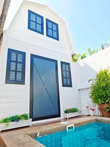 a white house with a blue garage door at Canary Pool Villa Bangsaen in Ban Hua Khao Sammuk