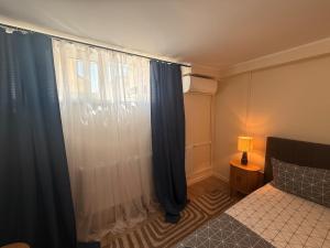 a bedroom with a bed and a window with curtains at Constanta Seaside Studio Demisol in Constanţa +4 photos