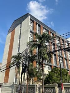 a tall building with palm trees in front of it at Sienna Living Setiabudi in Jakarta