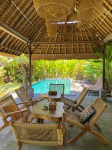 een terras met een tafel en stoelen en een zwembad bij SoulStar in Ubud