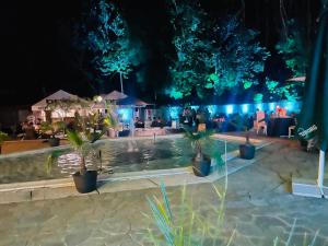 a pool with palm trees and a bar at night at Hotel Fantazia in Haskovo