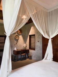 een slaapkamer met een bureau en een bed met gordijnen bij SoulStar in Ubud