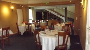 a restaurant with white tables and chairs and a staircase at La Cocotte Gourmande in Carantilly