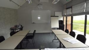 a classroom with tables and chairs and a white screen at La Cocotte Gourmande in Carantilly