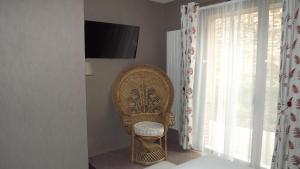 a wicker chair sitting in a room with a window at La Cocotte Gourmande in Carantilly