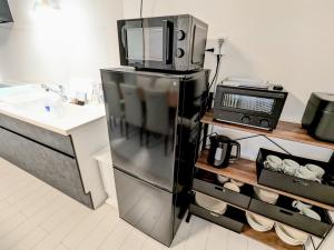 a kitchen with a black refrigerator and a microwave at Vacation House 3 in Funabashi