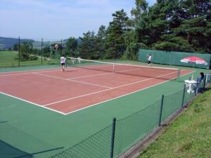 two people playing tennis on a tennis court at Hotel Kolonie in Křivoklát