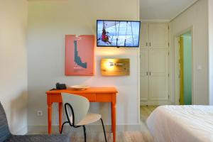 a bedroom with a desk with a chair and a tv at Hotel La Alfonsina in Santibáñez de Villacarriedo