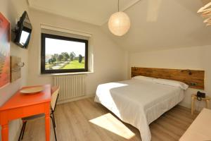 a bedroom with a bed and a desk and a window at Hotel La Alfonsina in Santibáñez de Villacarriedo