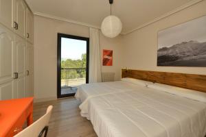 Un dormitorio con una gran cama blanca y una ventana en Hotel La Alfonsina en Santibáñez de Villacarriedo
