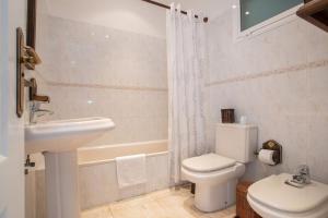 a white bathroom with a toilet and a sink at Paraíso Atlántico in Radazul +20 photos