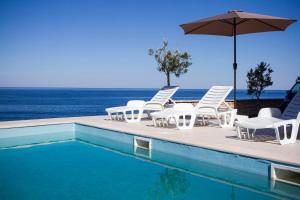 a group of chairs and an umbrella next to a swimming pool at Apartments Harmony in Utjeha +12 photos