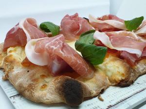 a pizza with meat and vegetables on a plate at Casa Gioconda Bed & Breakfast in Nuxis