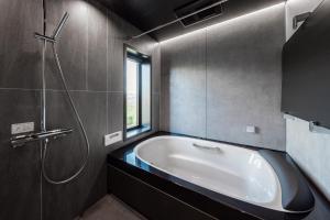 a bathroom with a bath tub and a window at Yugen Retreats Furano in Kami-furano +80 photos